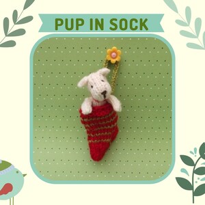 May include: A white knitted dog toy is inside a red and gold striped sock. The sock is hanging from a yellow flower with a green stem.