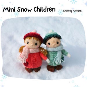Peut inclure: Deux poupées tricotées, intitulées "Mini Snow Children", sont habillées pour l'hiver. L'une porte un chapeau, un manteau rouges et une écharpe rose. L'autre porte un chapeau, un manteau verts et une écharpe bleue. Les poupées sont dans la neige.