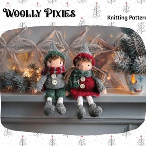 Op de afbeelding: Twee gebreide kabouterpoppen, één in groen en grijs, de andere in rood en groen, zitten naast elkaar. Ze dragen hoeden en sjaals, met de tekst "WOOLLY PIXIES" erboven. De afbeelding bevat ook de tekst "Knitting Pattern".
