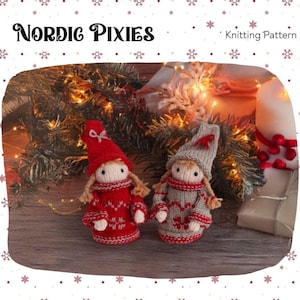 Könnte beinhalten: Zwei gestrickte Nordic Pixies-Puppen, eine rote und eine graue, mit passenden Mützen und Pullovern. Die Puppen haben blonde Garnhaare und posieren vor einem Weihnachtsbaum und einer brennenden Kerze. Die Worte "Nordic Pixies" und "Knitting Pattern" stehen oben.