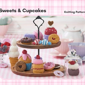 Könnte beinhalten: Ein zweistöckiger Holzservierständer zeigt eine Sammlung gestrickter Süßigkeiten, darunter Cupcakes, Donuts und Bonbons. Die Cupcakes sind mit rosa, gelbem und blauem Zuckerguss verziert, während die Donuts Schokoladen- und rosa Glasur haben. Der Text "Sweets & Cupcakes" und "Knitting Pattern" ist sichtbar.