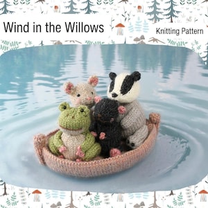 May include: A knitted boat carrying four animal figures: a green frog, a beige mouse, a black mole, and a badger with a black and white head. The boat is pink and floats on a blue surface. The text "Wind in the Willows" and "Knitting Pattern" are at the top.