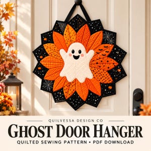 Puede incluir: Un colgador de puerta acolchado con un fantasma blanco central rodeado de pétalos de tela naranja y negra. El diseño incluye patrones de telarañas, murciélagos y calabazas pequeñas. El texto inferior dice QUILVESSA DESIGN CO GHOST DOOR HANGER.