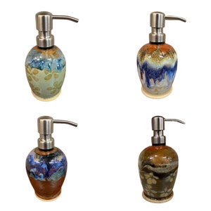 May include: Four ceramic soap dispensers with stainless steel pumps. Each dispenser has a unique glaze pattern in shades of blue, brown, and white.