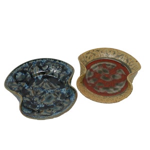 May include: Two ceramic serving dishes with a wavy edge. One dish is blue and brown with a mottled glaze. The other dish is yellow and brown with a red glaze.