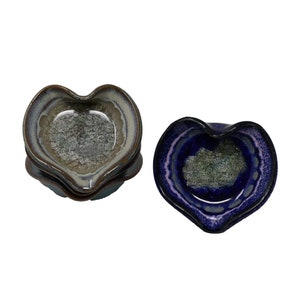 Op de afbeelding: Hartvormige keramische schaaltjes in tinten blauw, grijs en bruin. De schaaltjes hebben een textuur aan de binnenkant en een glanzende afwerking. De set bevat meerdere schaaltjes, perfect voor het serveren van kleine porties of als decoratieve accenten.