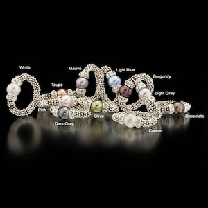 May include: A set of ten silver rings with a pearl in each ring. The pearls are in different colors, including white, mauve, light blue, burgundy, light gray, pink, dark gray, olive, cream, and chocolate.