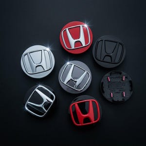以下が含まれることがあります： クローム、マットブラック、グロスブラック、レッド、シルバーなど、様々な仕上げのホンダ製ホイールセンターキャップ7個セット。各キャップにはホンダのHロゴが浮き彫りにされています。1つは裏面が見えており、成形されたプラスチックのディテールが確認できます。