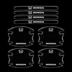 May include: A set of four black Honda door handle protective covers and four matching black Honda door sill protector strips. Each piece features the white Honda logo and text, with a glossy finish and contoured edges for vehicle application.