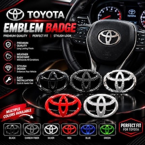 Pode incluir: Uma coleção de emblemas Toyota em vários acabamentos, incluindo preto, fibra de carbono, prata, vermelho, azul e verde. Os emblemas apresentam o logótipo da Toyota e estão dispostos numa superfície escura em frente a um volante.
