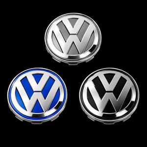 Könnte beinhalten: Drei kreisförmige Volkswagen Radnabendeckel mit dem ikonischen VW-Logo in Silber. Eine Kappe hat einen silbernen Hintergrund, eine einen leuchtend blauen Hintergrund und die dritte einen schwarzen Hintergrund. Jedes Emblem hat ein poliertes Metallfinish.