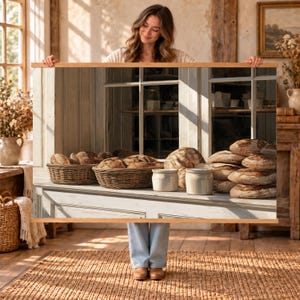 May include: A rectangular wall hanging featuring a printed image of a bakery scene. The print displays two woven wicker baskets filled with round loaves of bread, two light-colored ceramic jars, and a stack of crusty bread loaves on a ledge.