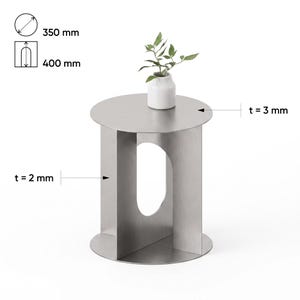 May include: A silver metal side table with a circular top and a base featuring a central oval cutout. The table has a diameter of 350 mm, a height of 400 mm, a top thickness of 3 mm, and a base thickness of 2 mm. A small white vase sits on top.