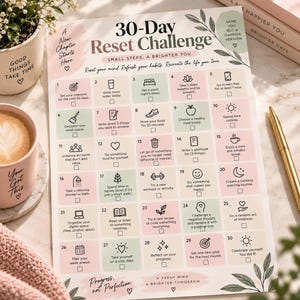 May include: A 30-Day Reset Challenge printable tracker sheet with a grid of numbered daily tasks, each featuring a small icon and a checkbox. The design uses a soft color palette of pastel pink, green, and cream with botanical leaf illustrations.