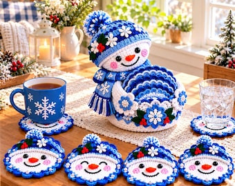 May include: A crochet snowman-shaped coaster holder with a matching blue and white scarf and pom-pom hat, containing several round snowman face coasters. The set features blue and white yarn, snowflake accents, and small red berry details.