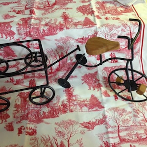 May include: A black metal toy wagon and tricycle set. The wagon has a wire frame and wheels. The tricycle has a wooden seat and wheels.