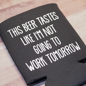 May include: Black neoprene can cooler with white text that reads "This beer tastes like I'm not going to work tomorrow."