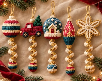 May include: Five crocheted Christmas ornaments featuring a striped ball, a red truck with a tree, a snow globe with a house, a teardrop shape, and a star, each with a gold hanging loop and a spiraled cream and gold tail ending in a small sphere.