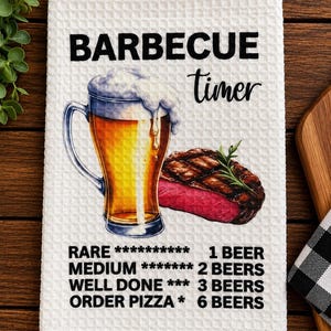 May include: A white waffle-weave kitchen towel featuring a graphic of a beer mug and a grilled steak. The text reads BARBECUE timer, with a chart listing cooking doneness levels from RARE to ORDER PIZZA, correlated to the number of beers consumed.