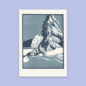 May include: A rectangular art print featuring a stylized winter landscape illustration. The scene depicts a large, snow-covered evergreen tree in the foreground, set against a dark blue sky with white specks and a distant, snow-capped mountain range.