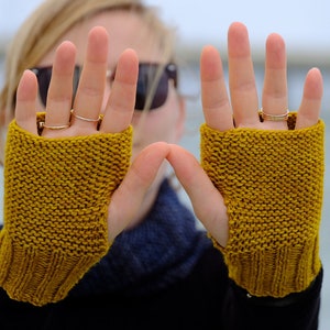 May include: A pair of yellow fingerless knitted gloves. The gloves are made of a soft, warm yarn and have a simple, classic design.