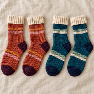 Può includere: Due paia di calzini all'uncinetto con polsino a coste. Il primo paio è color ruggine con strisce orizzontali gialle, rosa e viola scuro. Il secondo paio è color ottanio con strisce orizzontali verde chiaro, bianche e blu scuro.