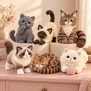 Op de afbeelding: Zes gehaakte kattenbeeldjes in verschillende houdingen en kleuren. De collectie bevat een grijze kat, een rekkende Siamees, een bruine cyperse kat, een ragdoll-achtige kat, een opgerolde luipaardkat en een pluizige witte kat met een bolletje wol.