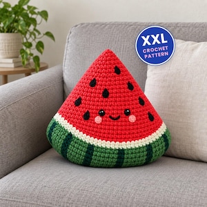 Könnte beinhalten: Ein dreieckiges Häkelkissen in Form einer Wassermelonenscheibe mit roter Oberseite, weißem Rand und grüner Basis. Das Kissen hat aufgestickte schwarze Kerne, ein lächelndes Gesicht mit rosa Wangen und ein blaues rundes Abzeichen mit XXL CROCHET PATTERN.