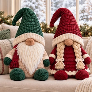 Puede incluir: Dos muñecos gnomos de ganchillo. El gnomo de la izquierda tiene un gorro verde oscuro, cuerpo beige y una larga barba de lana blanca. El gnomo de la derecha tiene un gorro rojo intenso, vestido rojo a juego y dos trenzas de lana rubia.