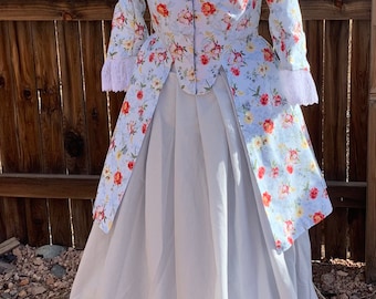 May include: A light blue floral print dress with a white underskirt. The dress features long sleeves with lace cuffs and a square neckline trimmed with white lace. The floral pattern includes red and yellow flowers.