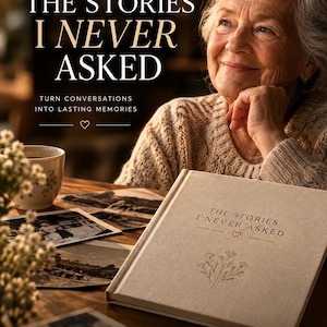 May include: A beige fabric-covered memory journal titled The Stories I Never Asked with a small floral illustration and heart icon on the cover. The journal is displayed alongside black and white photographs and a cup on a wooden surface.
