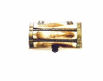 May include: A rectangular, antique-style box with a hinged lid and metal accents. The box is primarily cream-colored with brown streaks, and the edges are trimmed with gold-colored metal. A small, ornate latch secures the front.