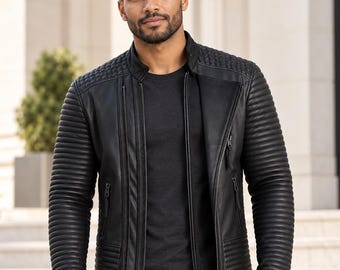 Può includere: Una giacca in pelle nera con colletto alla coreana, dettagli a coste sulle spalle e sulle maniche e tasche verticali con cerniera. La giacca è indossata sopra una t-shirt nera semplice e abbinata a jeans neri dal design elegante.