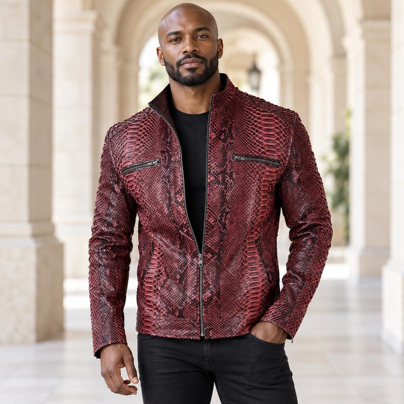 Peut inclure: Une veste &agrave; motif peau de serpent rouge fonc&eacute; et noir avec un col montant, une fermeture &eacute;clair frontale int&eacute;grale et deux poches de poitrine horizontales zipp&eacute;es. La veste est port&eacute;e sur un t-shirt noir avec un pantalon noir.