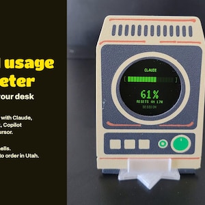 May include: A beige and dark gray rectangular AI usage meter with a circular screen displaying the text CLAUDE, a green progress bar, 61%, and RESETS 4H 17M SESSION. The device features three square buttons and one circular green button.