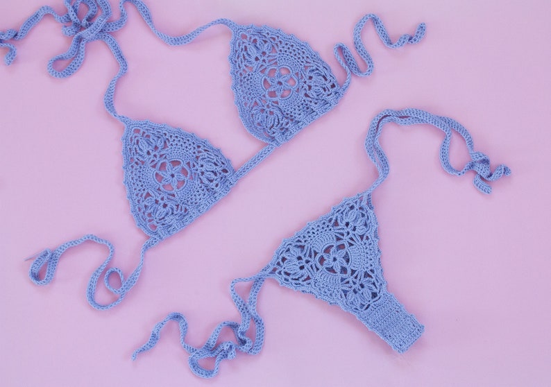 May include: A light blue crocheted bikini set with intricate floral patterns. The bikini top has adjustable straps and the bottom has a high-cut style.