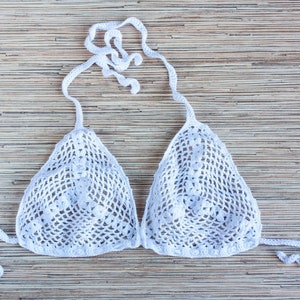 K&ouml;nnte beinhalten: Wei&szlig;er geh&auml;kelter Bikini-Oberteil mit einem Halterneck-Stil. Das Oberteil hat ein zartes, spitzenartiges Muster.