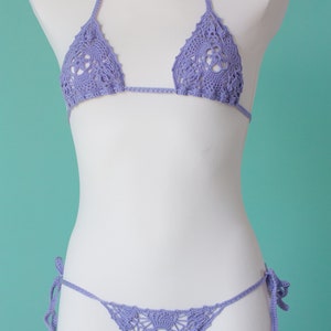 May include: A lavender crochet bikini top and bottom with a delicate floral pattern. The bikini top has adjustable straps and the bottom has ties on the sides.