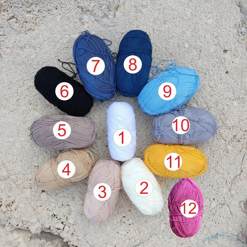 Puede incluir: Doce ovillos de lana en varios colores, incluyendo blanco, gris, azul, negro, marr&oacute;n, amarillo y rosa. Cada ovillo est&aacute; numerado del 1 al 12.