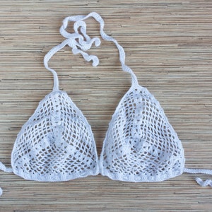 K&ouml;nnte beinhalten: Wei&szlig;er geh&auml;kelter Bikini-Oberteil mit einem zarten Muster. Das Oberteil hat verstellbare Tr&auml;ger und eine dreieckige Form.