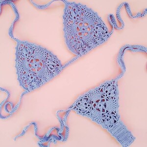 May include: A lavender crochet bikini top and bottom with a delicate floral pattern. The bikini is made with a soft, lightweight yarn and has adjustable straps.