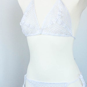 K&ouml;nnte beinhalten: Wei&szlig;er Bikini aus H&auml;kelspitze mit zartem Blumenmuster. Das Oberteil ist im Halstert-Stil mit verstellbaren Tr&auml;gern. Das Unterteil ist im Low-Rise-Stil mit B&auml;ndern an den Seiten.