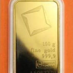 May include: A rectangular 100 g fine gold 999.9 bar encased in clear plastic packaging with an orange border. The gold bar features an embossed geometric logo, the text 100 g fine gold 999.9, a small rectangular logo, and the serial number AA067779.