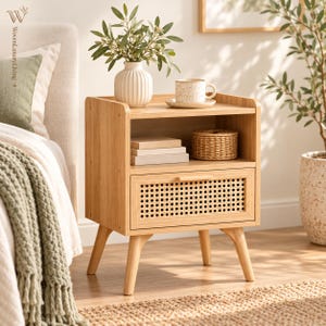 May include: A light wood nightstand featuring a single drawer with a woven cane front panel, an open storage shelf, and four tapered legs. The top surface holds a white ribbed vase with green foliage and a speckled ceramic mug on a saucer.