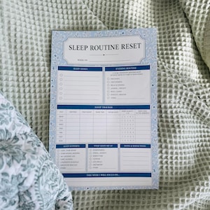 May include: A rectangular paper sleep routine reset planner with a light blue floral border. The document includes sections for sleep goals, evening routine, a weekly sleep tracker, sleep supports, obstacles, notes, and a focus area for the week.