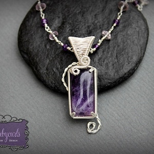 May include: A silver wire wrapped pendant necklace with a purple amethyst gemstone. The necklace features a delicate wire design and a small, intricate pendant.