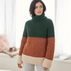 May include: A chunky knit roll-neck jumper featuring a colour-blocked design with a dark green upper section, a rust orange middle band, and a cream-coloured hem. The jumper has long sleeves and a ribbed texture throughout the collar and body.