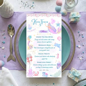 Op de afbeelding: Een rechthoekige menukaart met de titel Kiara Turns 5, voorzien van aquarelillustraties van zeemeerminnen, een dolfijn, een octopus en een narwal. Het menu bevat Under The Sea Bites, Mermaid's Main, Ocean Treats en Something Sweet.