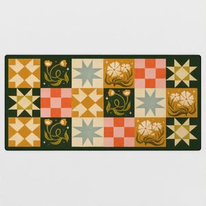 May include: A rectangular mat featuring a grid of squares with alternating patterns including eight-pointed stars, checkered blocks in pink and orange, and floral illustrations with white flowers and green stems on a dark green background.