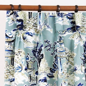 May include: Blue and white patterned curtains with a Japanese garden design. The curtains are hung on a wooden rod with metal rings.